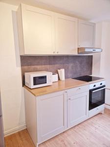een keuken met witte kasten en een magnetron bij Nordseeluft Apartment in Bremerhaven