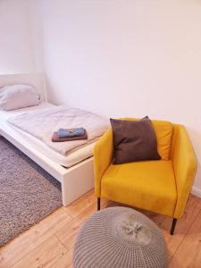 een slaapkamer met een gele stoel en een bed bij Nordseeluft Apartment in Bremerhaven
