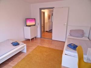 een woonkamer met 2 bedden en een televisie bij Nordseeluft Apartment in Bremerhaven