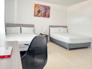 a hotel room with two beds and a desk with a chair at Hotel Vanguardia Natural in Villavicencio