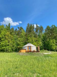 Eine Jurte auf einem Feld mit Bäumen im Hintergrund in der Unterkunft 4rest Camp in Pawłowo