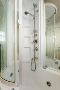 a shower in a bathroom with a mirror at Veeve - The Gallery of Colour in London