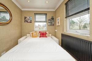 a bedroom with a large white bed with two windows at Veeve - The Gallery of Colour in London