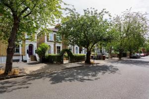 a street with trees in front of a house at Veeve - The Gallery of Colour in London