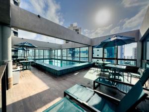 un edificio con una piscina con mesas y sombrillas en Flat em Boa Viagem Rooftop 470 Conforto e Localização privilegiada, en Recife