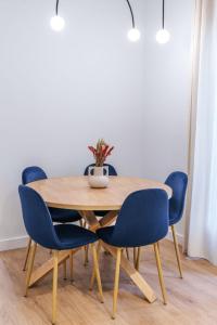 a wooden table with blue chairs and a vase on it at New Luxury flat next to Gran Vía in Madrid