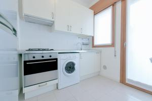eine weiße Küche mit einer Waschmaschine und einem Fenster in der Unterkunft QUEEN HOME GEMMA in Mestre