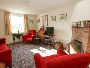 een woonkamer met rode stoelen en een open haard bij Chenies in Weymouth