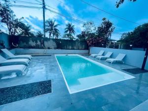 a swimming pool with lounge chairs next to a fence at Le refuge rafraîchissant in Montjoly
