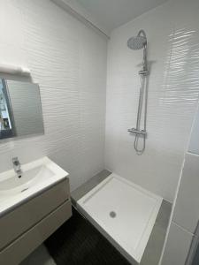 a white bathroom with a sink and a shower at Le refuge rafraîchissant in Montjoly