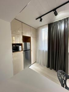 a small kitchen with a refrigerator and a window at Fresh and cozy apartmrent in Yakkasaray