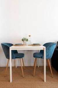 una mesa blanca con dos sillas azules sentadas al lado en Vieux Lille -Nice studio neat and fully equipped !, en Lille 10 fotos más
