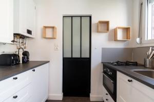 een keuken met witte kasten en een zwarte deur bij Vieux Lille Bright fully-equipped apartment! in Lille