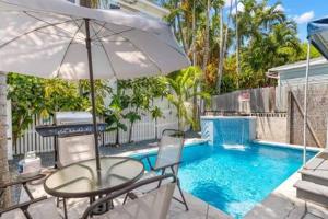 a table and chairs with an umbrella next to a pool at Poolside Retreat in Key West