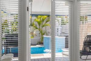 a window with a view of a pool and buildings at Poolside Retreat in Key West +10 photos