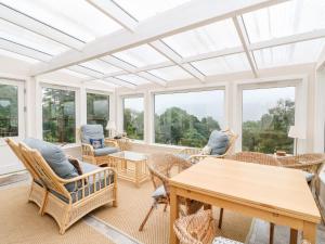 a conservatory with a table and chairs and windows at Waterfall Cottage in Aberfeldy