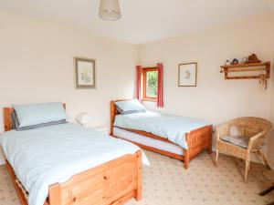 two beds in a room with a chair and a window at Waterfall Cottage in Aberfeldy