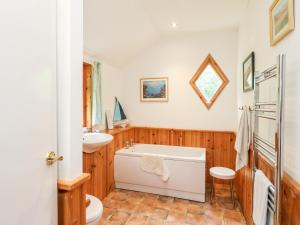a bathroom with a tub and a toilet and a sink at Waterfall Cottage in Aberfeldy