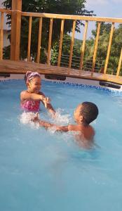 two children are playing in a blue swimming pool at Belle Air Seaview (2 BDRM 2 King) in Runaway Bay