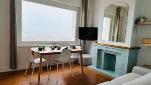 ein Wohnzimmer mit Tisch und Kamin in der Unterkunft Appartement la capitainerie in Cayeux-sur-Mer