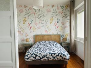 1 dormitorio con 1 cama y papel pintado con motivos florales en Appartement la capitainerie, en Cayeux-sur-Mer