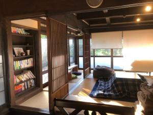 sala de estar con estante de libros y sofá en Antique Villa Lotus（古民家ロータス） en Tsukuba