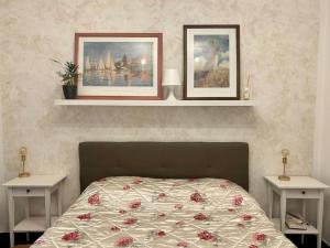 ein Schlafzimmer mit einem Bett mit zwei Tischen und zwei Bildern in der Unterkunft Bilocale ristrutturato, Lingotto in Turin