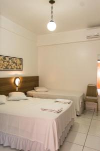 two beds in a room with white walls at Grand Prix Hotel in Cascavel