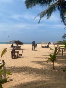 a beach with tables and umbrellas on the sand at Sandaru villa in Induruwa