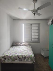um quarto com uma cama e uma ventoinha de tecto em Astúrias no Guarujá