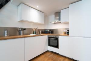 cocina blanca con suelo de madera y armarios blancos en Bright 3-bedroom 2-bathroom flat., en Lille