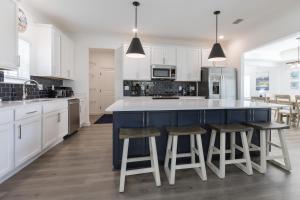a kitchen with white cabinets and a blue island with stools at Wolf Bay Hangout in Coffeyville