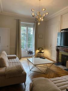 ein Wohnzimmer mit einem Sofa, einem Tisch und einem TV in der Unterkunft Belges in Lyon