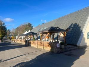 a restaurant with tables and umbrellas on the side of a building at Pinehurst, 65 Golf View Lodge in Jedburgh