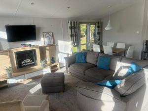 un soggiorno con divano e TV di Pinehurst, 65 Golf View Lodge a Jedburgh