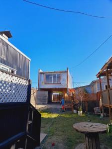 a backyard with a house and a wooden table at Cabaña León in Puerto Natales