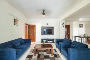 Sala de estar con 2 sofás azules y mesa de centro en Mistyblue Stays, en Bangalore