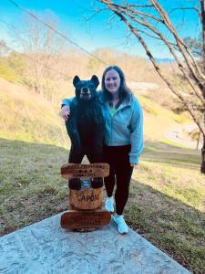 une femme est debout à côté d'une statue d'un ours dans l'établissement South Side Serenity, à Sevierville
