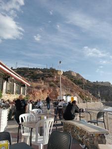 a group of people sitting at tables on the beach at Habitaciónes Privadas Cartagena Murcia in Cartagena