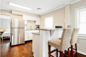 una cocina con nevera y un bar con sillas en Beachwalk #2 8 minute walk to the Beach, en Virginia Beach
