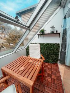 a wooden table and chairs on a balcony with windows at Schönbrunn Gardens Vienna Apartment in Vienna