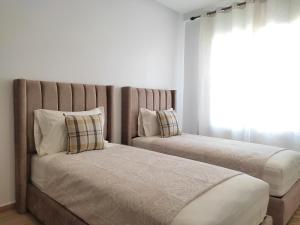 a bedroom with two beds and a window at DLX03 - Appartement Deluxe 2 chambres - Centre Ville Oujda in Oujda