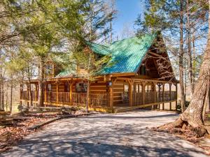 una cabaña de madera en el bosque con techo verde en Big Kahuna Lodge, en Sevierville