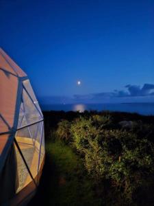 uma tenda com a lua no céu e no oceano em Geodome with sea views near Pendine em Pendine