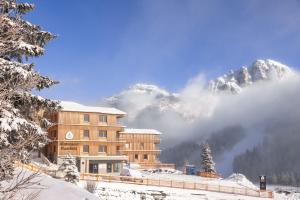 ein Gebäude im Schnee mit Bergen im Hintergrund in der Unterkunft "Home to Enjoy" Premium Appartement in Sonnenalpe Nassfeld