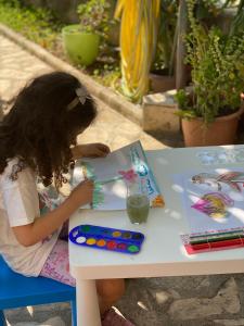 Una bambina seduta a un tavolo a fare un dipinto di Family Apartments Vesna- 100 m Beach -Center Crikvenica a Crikvenica