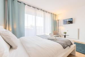 ein Schlafzimmer mit einem weißen Bett und einem großen Fenster in der Unterkunft Close to the city centre - Appartment confortable in Lille