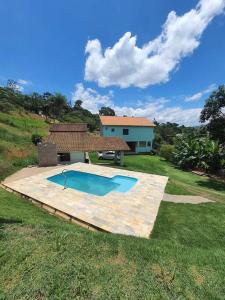 une arrière-cour avec une piscine et une maison dans l'établissement Chácara ( Dona Juju) super confortável em Igarata/SP!, à Igaratá
