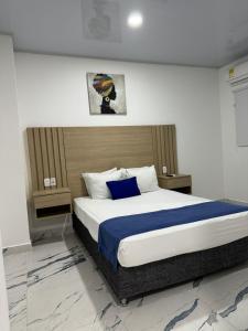 a bedroom with a large bed with a blue pillow at Hotel ITACO in Cartagena de Indias