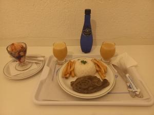 um tabuleiro com um prato de comida e dois copos de sumo de laranja em Motel Disco Verde Congonhas 1 em São Paulo